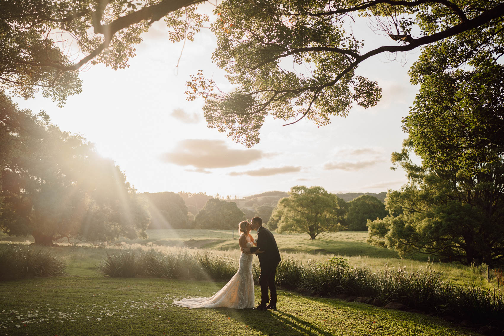 Bride and groom kissing under a tree at sunset at Frida's Field