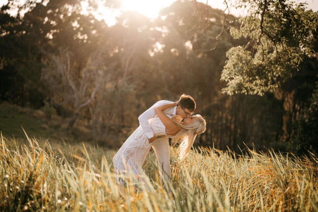 Bride and groom kissing at sunset on hilltop at Gold Coast wedding venue Pioneer Country
