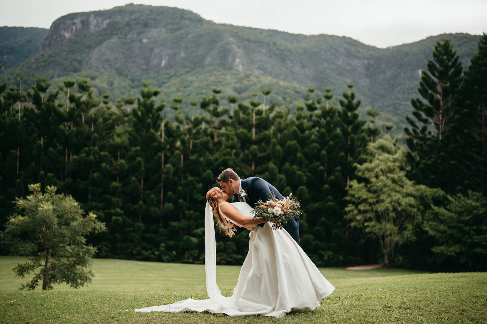 Bride and groom dip kissing with mountain views at a wedding at The Bower Estate