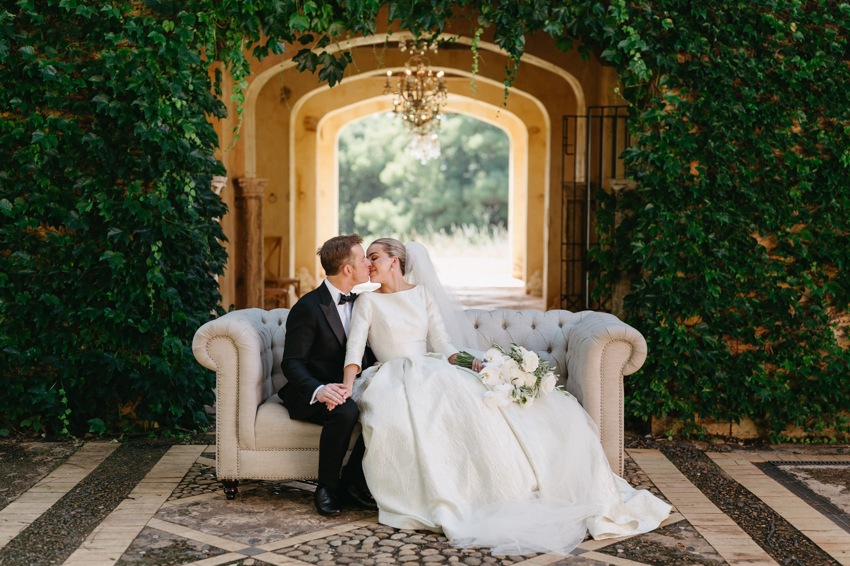 Newlyweds on Chesterfield lounge at Deux Belettes wedding in Byron Bay